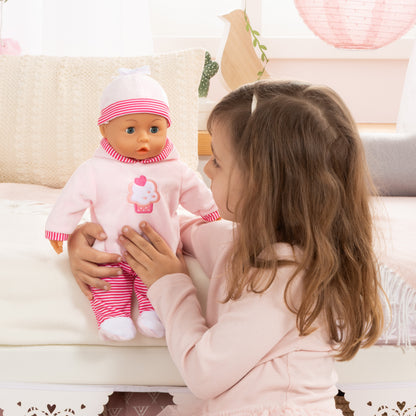 Child touching pink baby doll with striped hat and pacifier on a couch
