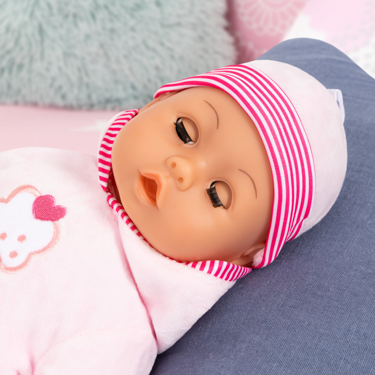 Side view pink baby doll with striped beanie, cupcake hoodie, and pacifier