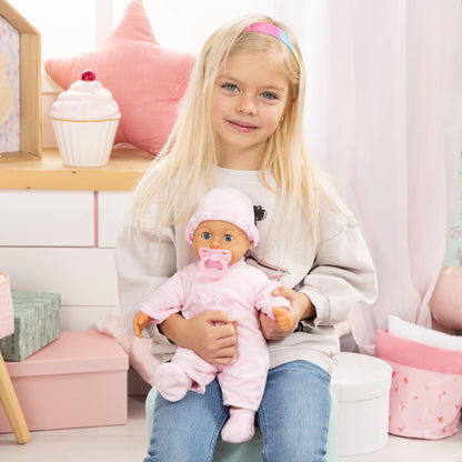 Pink baby doll wearing frilly hat and striped dress with pacifier, cradled in arms.