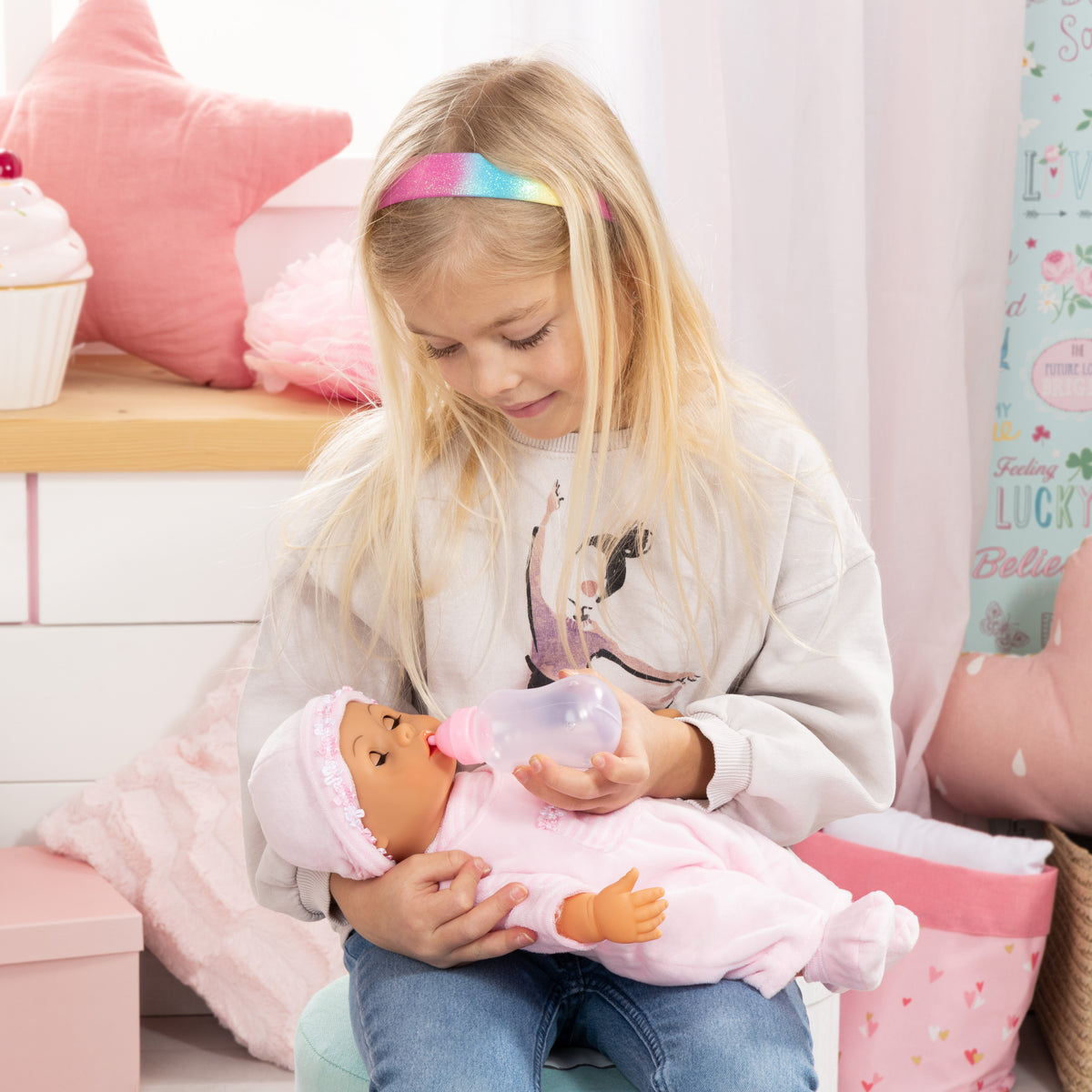 Pink baby doll with frilly hat and pacifier, dressed in light pink striped outfit.