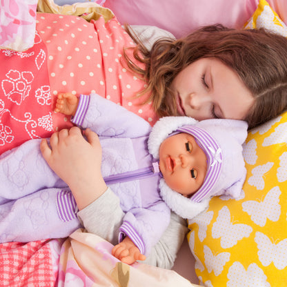 Interactive soft baby doll in purple hood with pacifier, lying on bed with child