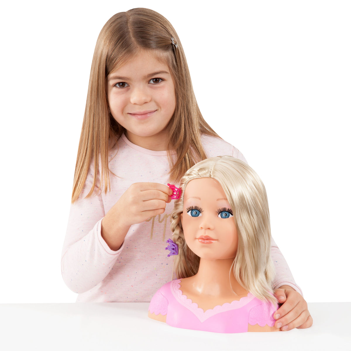 Child adjusting a blonde doll head with pink hair clip and pink dress top