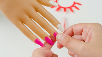 Hands applying pink nail tips to a doll finger with a small nail accessory