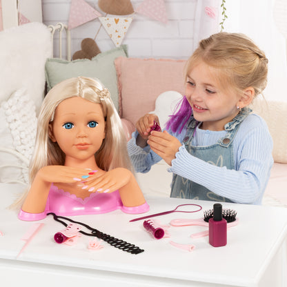 Blonde styling head doll as a child holds a nail tool beside the manicure kit