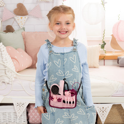 Child holding a pink manicure kit with brushes, bottles, and comb for styling head