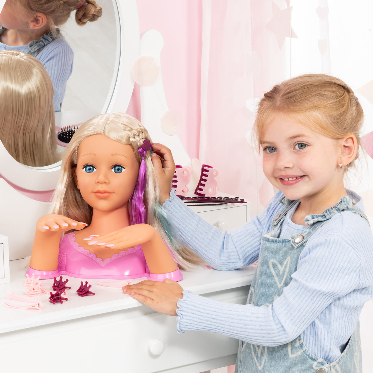 Blonde doll styling head with long hair as a child brushes and adjusts purple clips
