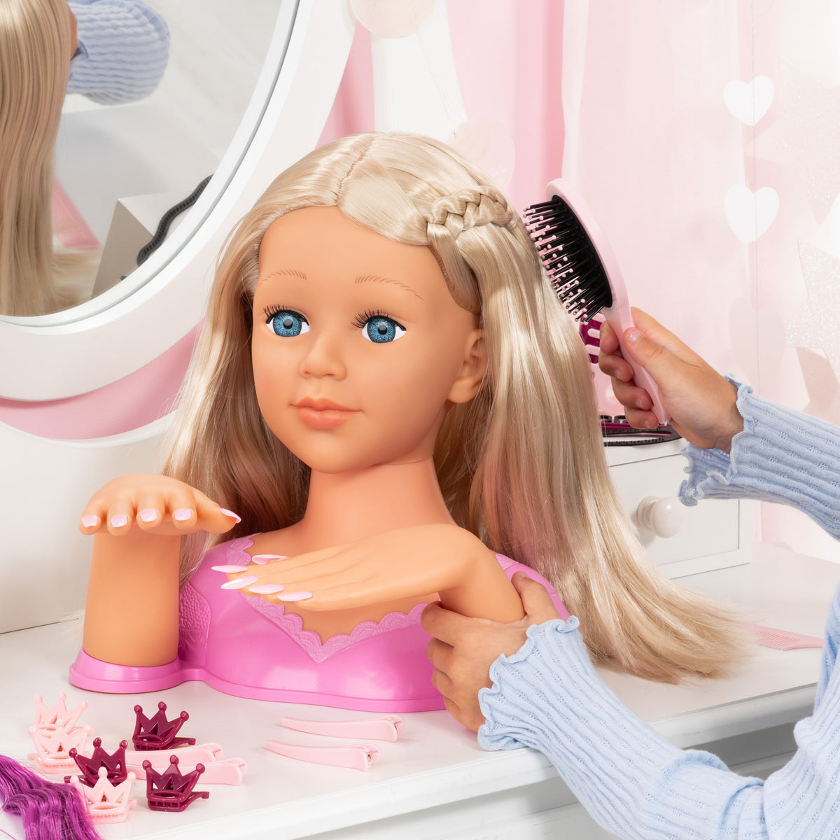 Blonde doll styling head with long hair while a child brushes near the top