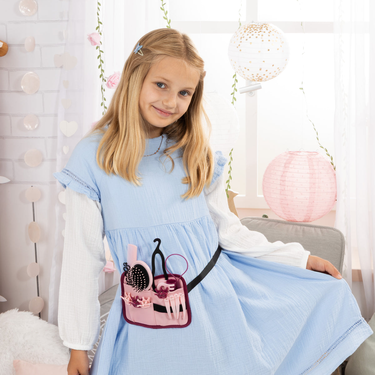 Child holding a hair styling tool pouch with brush and comb accessories