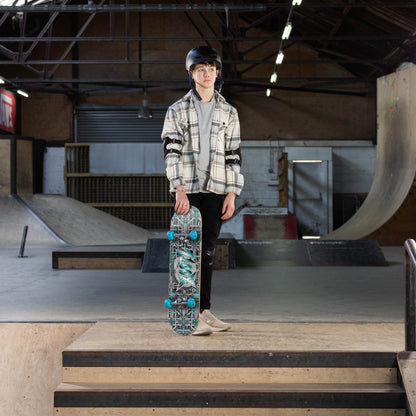 Person holding a complete skateboard with dark graphic deck and teal wheels