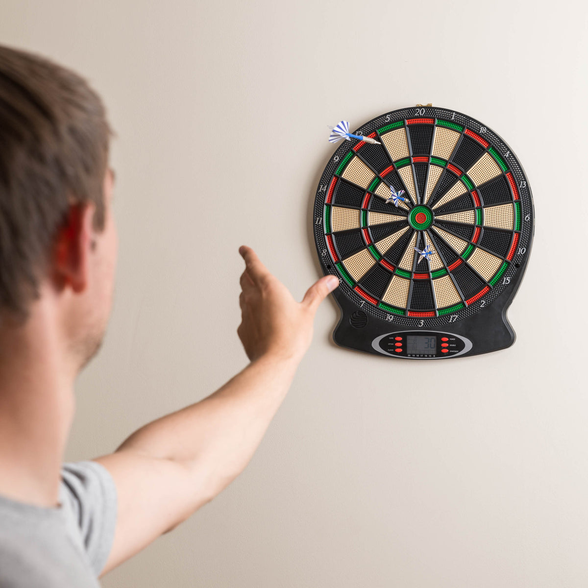 Electronic dartboard with scoring screen and darts stuck in the target