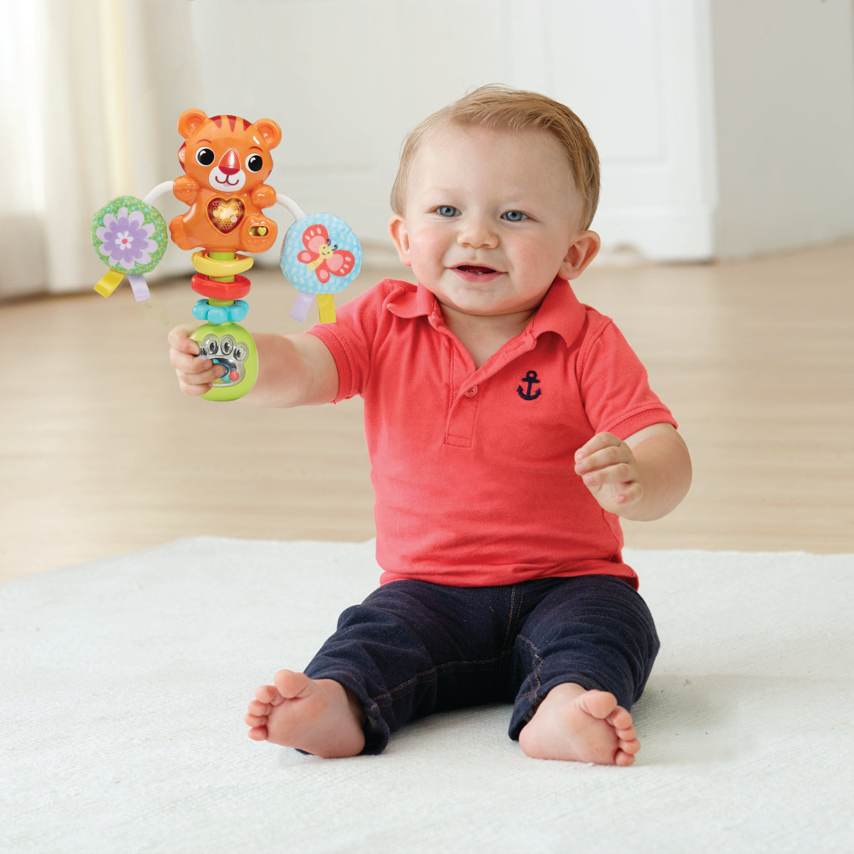 Baby holding orange tiger rattle toy with stacked rings and fabric teether balls