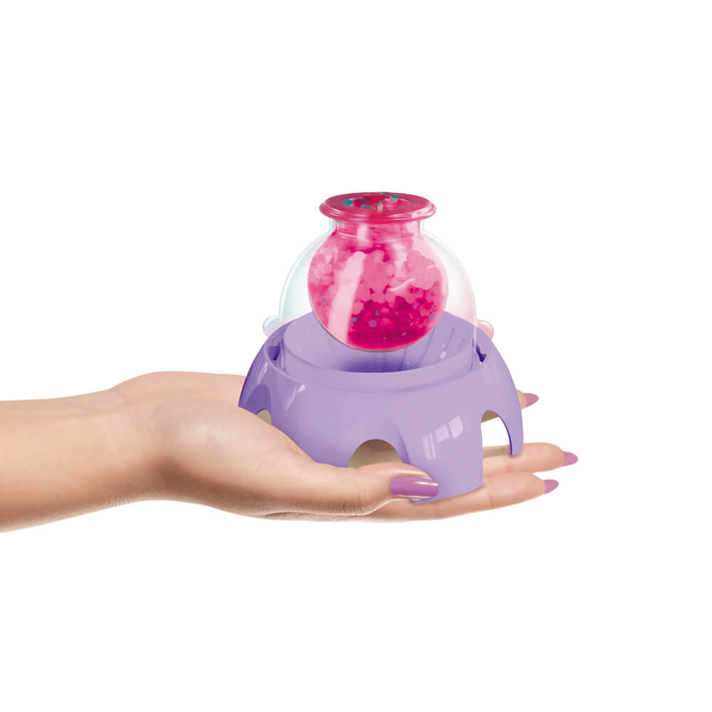 Hand holding purple mini squishy maker base with clear bottle and pink gel inside.