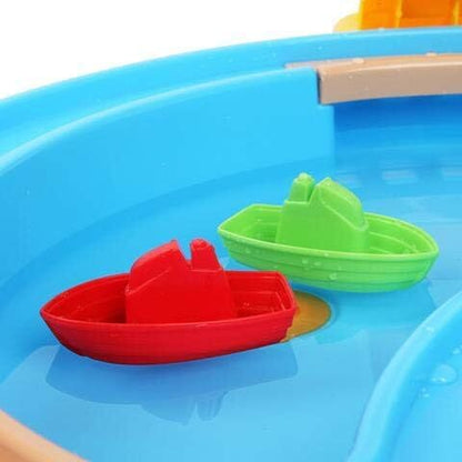 Blue basin with red and green toy boats floating near beige ramp
