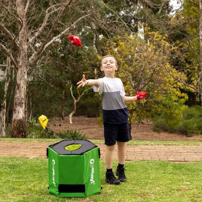 Child tossing red beanbags toward green cube and yellow disc target on lawn